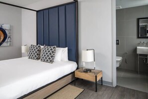 A modern hotel room with a bed, bedside table, lamp, and a view into the bathroom. - Rendale | Junior Suite | Near South Beach | Oaxacan Dining | 2 Units (Miami Beach)