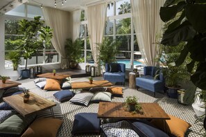 A spacious indoor area with multiple seating arrangements, large windows, and potted plants. - Rendale | Junior Suite | Near South Beach | Oaxacan Dining | 2 Units (Miami Beach)