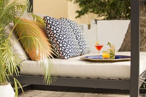 Un canapé avec des coussins à motifs, un plateau avec des boissons et une plante en pot.