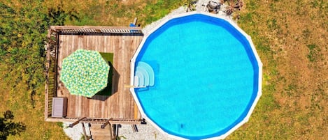 Vue aérienne d’une propriété dotée d’une piscine, d’une terrasse en bois et d’un espace salon abrité.