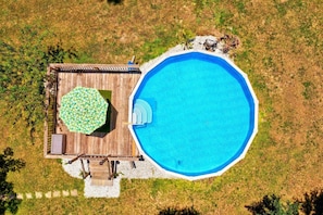 Vista aérea de una propiedad con piscina, terraza de madera y zona de estar cubierta.