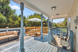 Eine überdachte Terrasse mit Holzbank, einer gepolsterten Sitzecke und einer Treppe, die zu einer oberen Ebene führt.