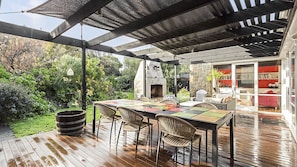 Eine Terrasse im Freien mit Holzdeck, Tisch und Stühlen sowie einem Steinkamin.