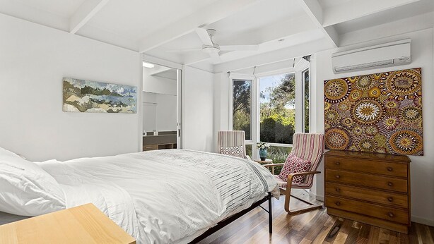 A bedroom with a bed, a dresser, a chair, and a large window. - Barrambeet - Point Lonsdale (POINT LONSDALE)