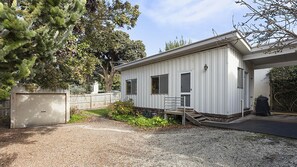 Ein eingeschossiges Gebäude mit überdachter Veranda, Garage und Kiesweg.