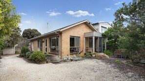Ein zweistöckiges Haus mit Backsteinfassade, einer Veranda und einem Schotterweg.