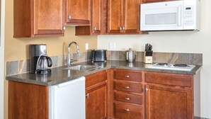 A kitchen with wooden cabinets, a white microwave, a coffee maker, and a stove.