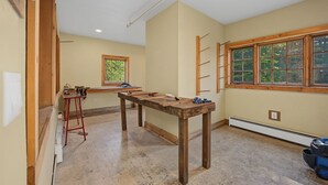 Una stanza con un grande tavolo di legno, una finestra vista su del verde e una scala appoggiata al muro.