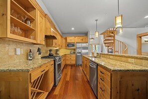 Eine Küche mit Holzausstattung, Granit Arbeitsplatten und Edelstahlgeräten, inklusive Backofen.