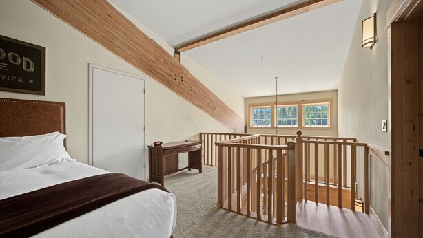 Una camera da letto con un letto, una scrivania, una finestra e una scala in legno.