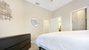 Un dormitorio con cama, cómoda, espejo y puerta que da a otra habitación.