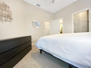 A bedroom with a bed, a dresser, a mirror, and a door leading to another room. - Upscale Living in Heart of Tampa, Courtyard Views (Tampa)