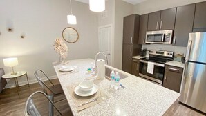 Una cocina moderna con encimeras de granito, electrodomésticos de acero inoxidable y una isla central con asientos.