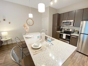 A modern kitchen with granite countertops, stainless steel appliances, and a central island with seating. - Upscale Living in Heart of Tampa, Courtyard Views (Tampa)