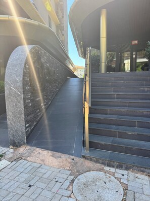 Un edificio moderno con fachada de piedra y una escalera que conduce a la entrada.