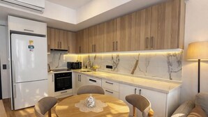 Cozinha moderna com armários de madeira, uma geladeira branca e um espaço de refeições com uma mesa redonda.