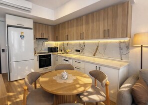 Eine moderne Küche mit Holzschränken, einem weißen Kühlschrank und einem Essbereich mit einem runden Tisch.