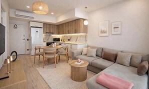 A modern kitchen with wooden cabinets, a dining area with a round table and chairs, a sofa with cushions, and a small round coffee table. - Royal Grand Exculisive luxury apartment in charming Alanya (Alanya)