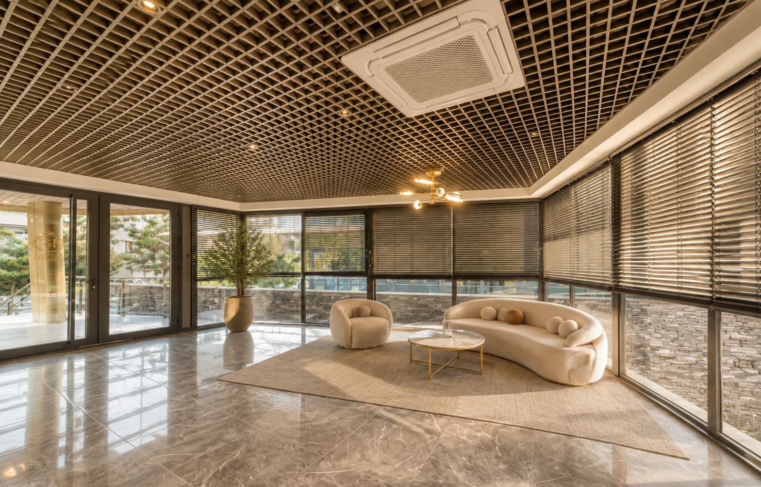 Une pièce spacieuse dotée d’un plafond au design moderne, de grandes fenêtres et d’un coin salon avec un canapé et une table basse.