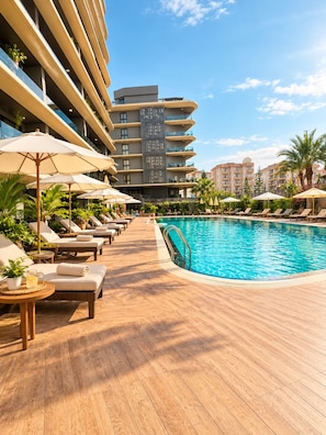 A poolside area with lounge chairs and umbrellas, a swimming pool, and a modern building with balconies. - Royal Grand Exculisive luxury apartment in charming Alanya (Alanya)