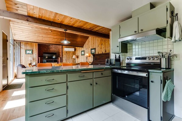 A kitchen with a central island, wooden ceiling, and a built-in oven.