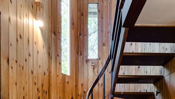 Un escalier en bois avec une rampe métallique menant à un palier.