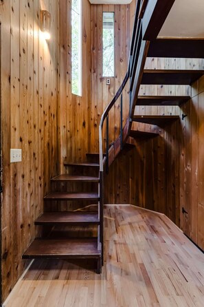 Eine Holztreppe mit Metallgeländer, das zu einer Zwischenebene führt.