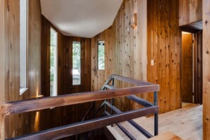 A wooden interior with a staircase and a view of the outdoors.