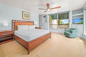 Ein Hotelzimmer mit einem großen Bett, einem Deckenventilator, einem Fenster mit Ausblick, einem Fernseher und einem Sessel.