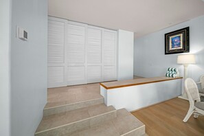 A hotel room with a wooden reception desk, a chair, a lamp, and a framed picture on the wall. - Palms at Wailea Villa 404 Garden Deluxe 2 BD 2 BA (Wailea)