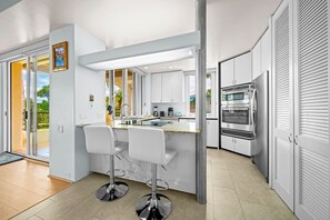 Eine moderne Küche mit einer zentralen Kochinsel, Edelstahlgeräten und einer Glastür zum Balkon.