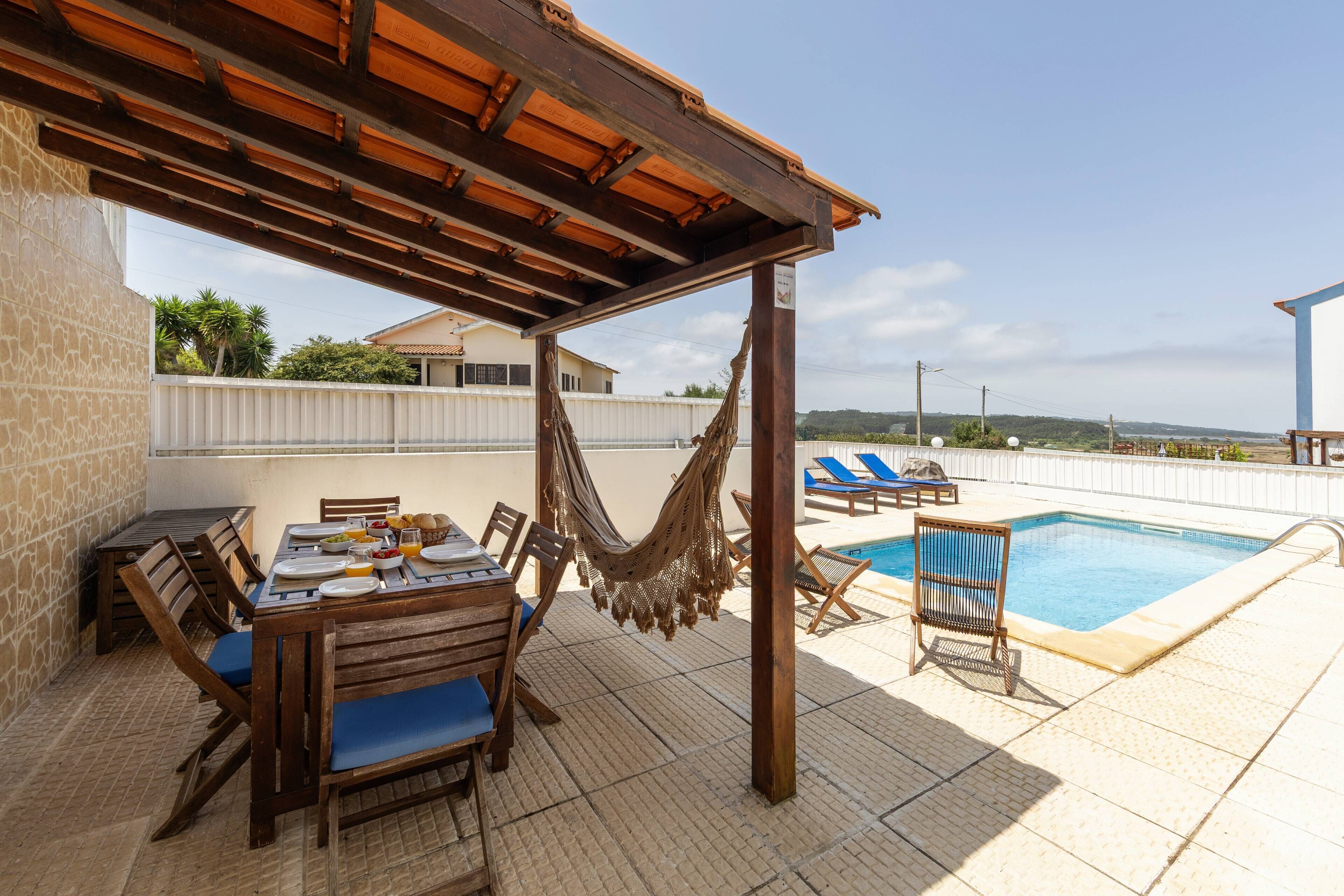 Terraço no telhado com piscina, área de refeições e redes.