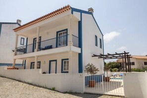 A two-story building with a balcony, a gated entrance, and a small garden area. - Casa Burgues Mar & Lagoa - Private Pool (Óbidos)