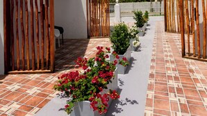 A courtyard with a tiled floor, a row of planters with flowers, and a clear sky. - Aruba Vibe Apartments #5 | A charming place near the beaches and the city center (Oranjestad)