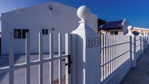 A white building with a blue door, a white fence, and a clear blue sky. - Aruba Vibe Apartments #5 | A charming place near the beaches and the city center (Oranjestad)