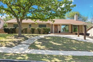 A residential house with a front porch, a large tree, and a well-maintained lawn. - 3-bedroom house near the San Antonio Quarry (San Antonio)