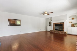 A spacious living room with hardwood flooring, a fireplace, and a ceiling fan. - 3-bedroom house near the San Antonio Quarry (San Antonio)