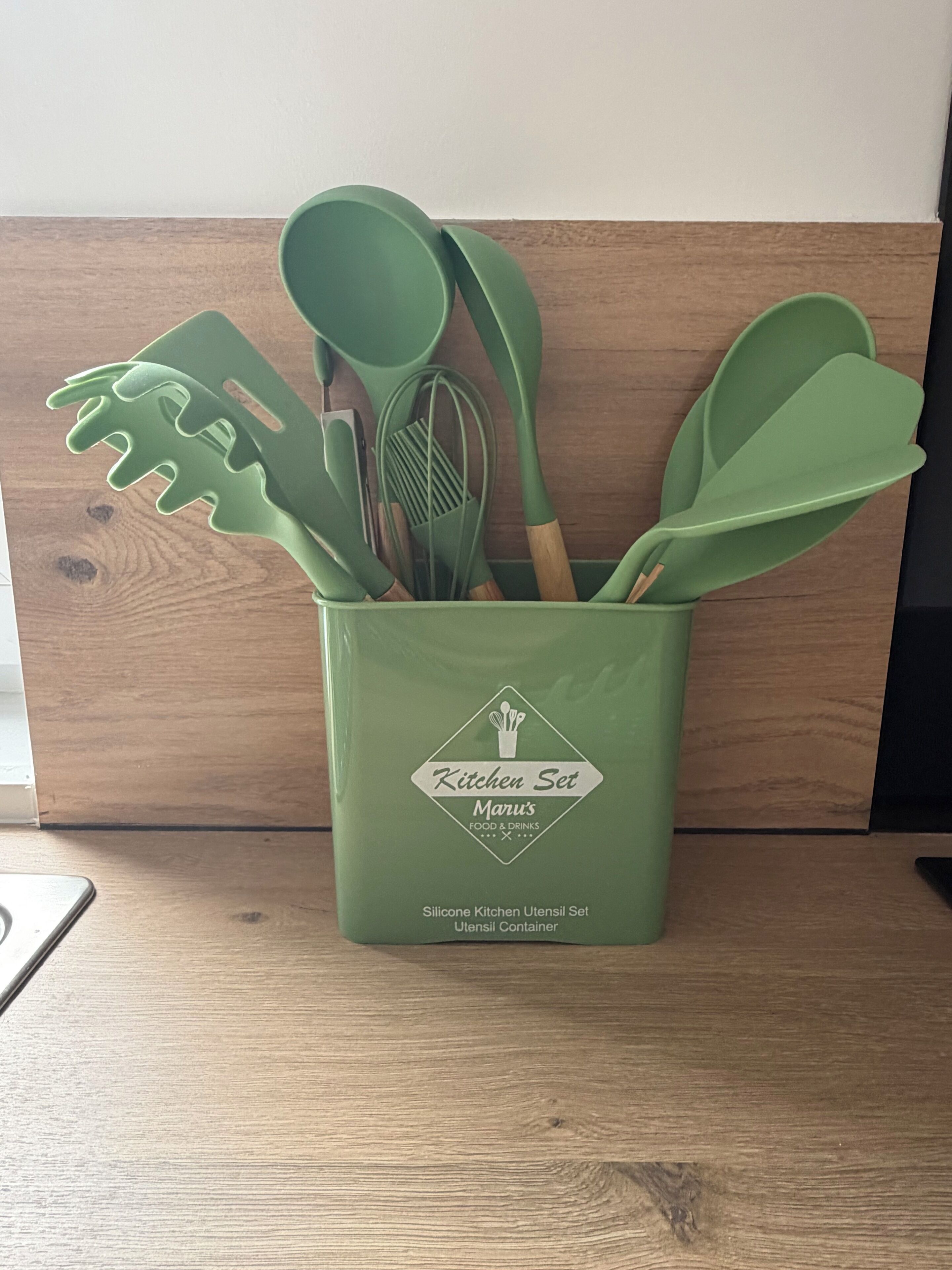 A green silicone kitchen utensil set in a container with a logo and text indicating it's from Maru's.