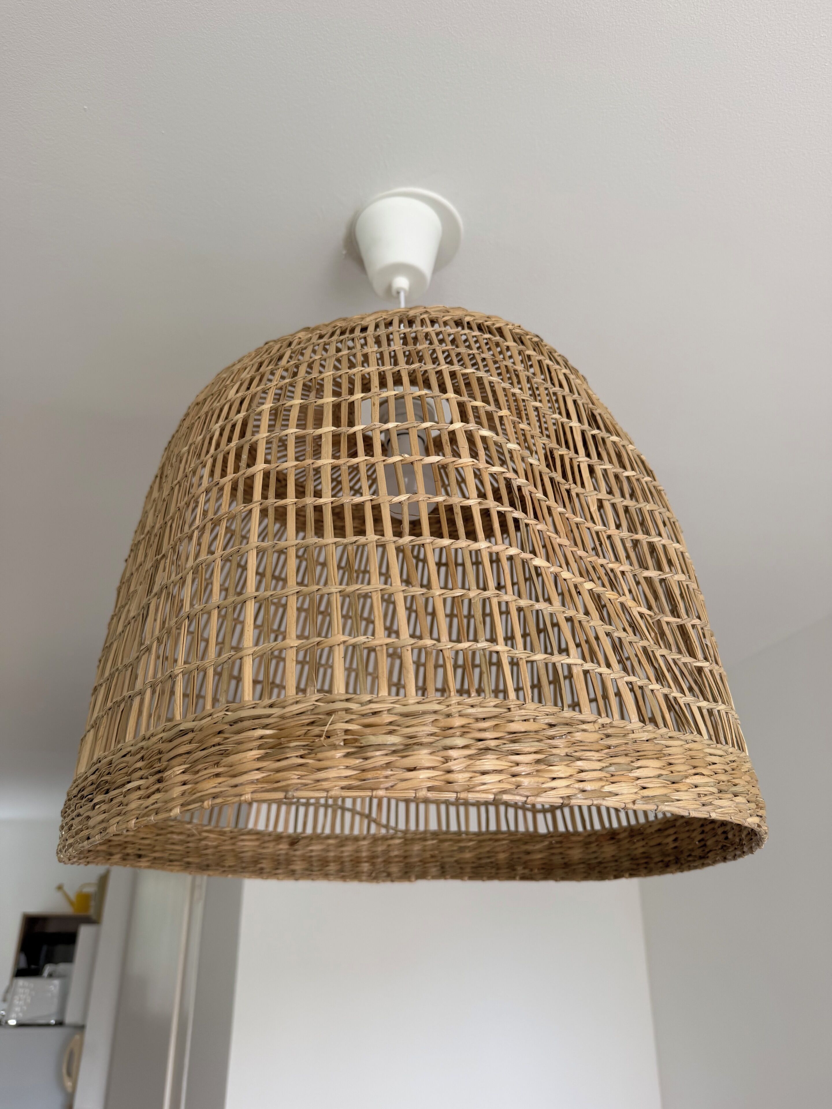 A woven rattan pendant light fixture with a white ceiling mount.