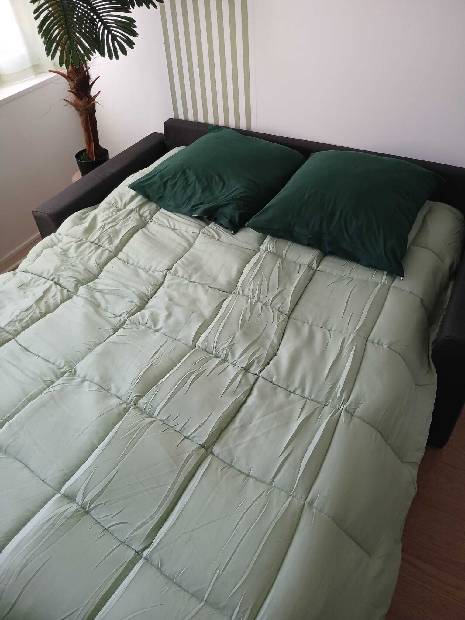 A bed with a quilted bedspread and two pillows.