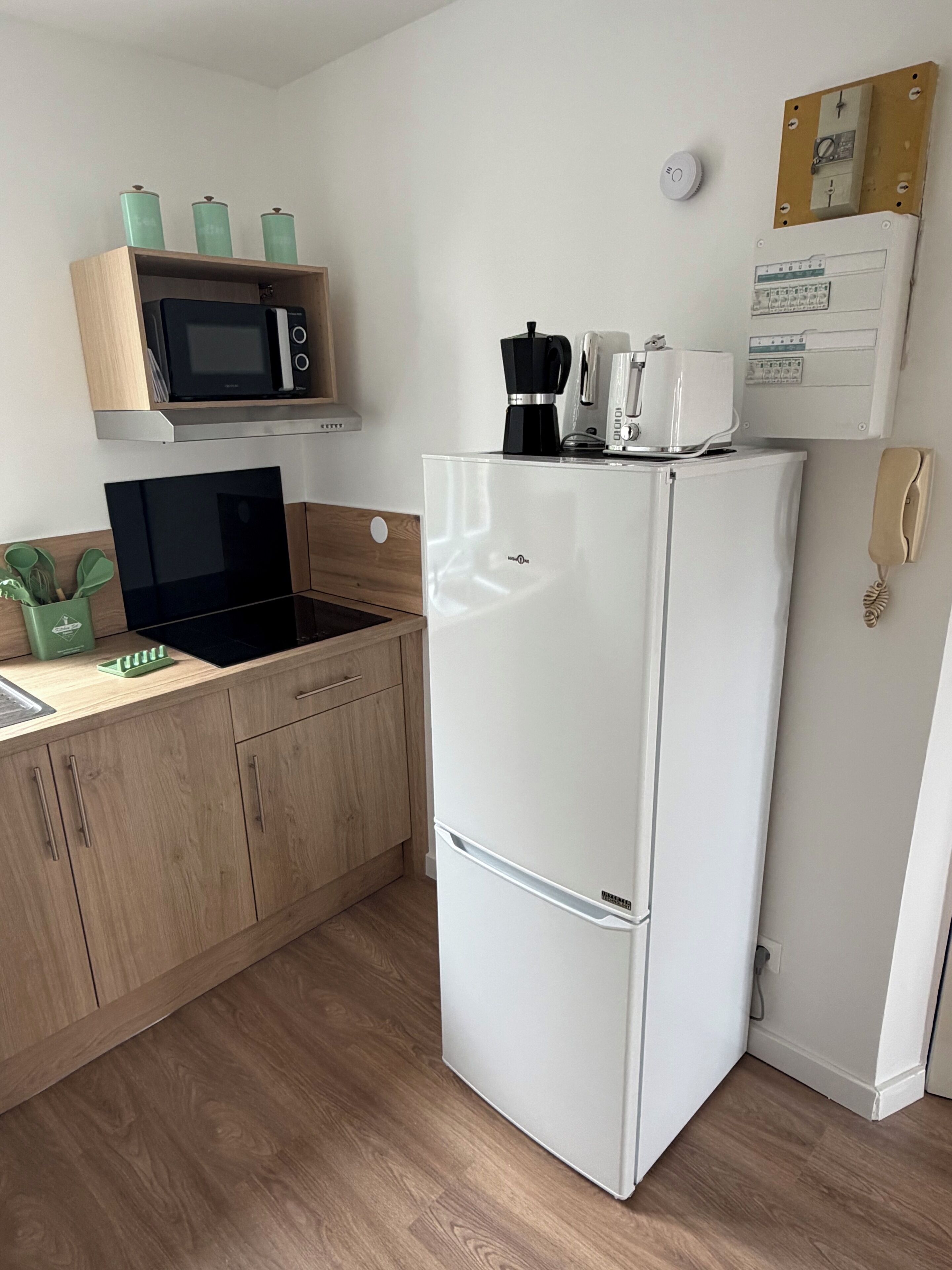 Een keuken met een magnetron, koffiezetapparaat en een koelkast.