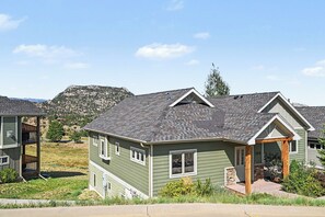 Ein Wohnhaus mit geneigtem Dach, einer Veranda und Blick auf eine gebirgige Landschaft.