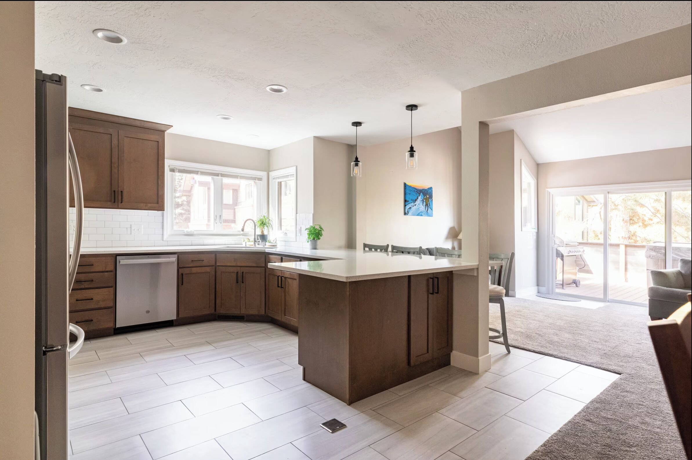 A modern kitchen with a central island, wooden cabinets, and a large window.