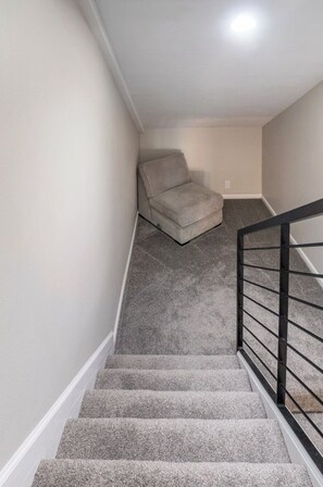 A carpeted staircase with a handrail, leading to a landing where a chair is placed. - Spacious 5-bedroom condo, base of Big Cottonwood Canyon in Cottonwood Heights (Cottonwood Heights)