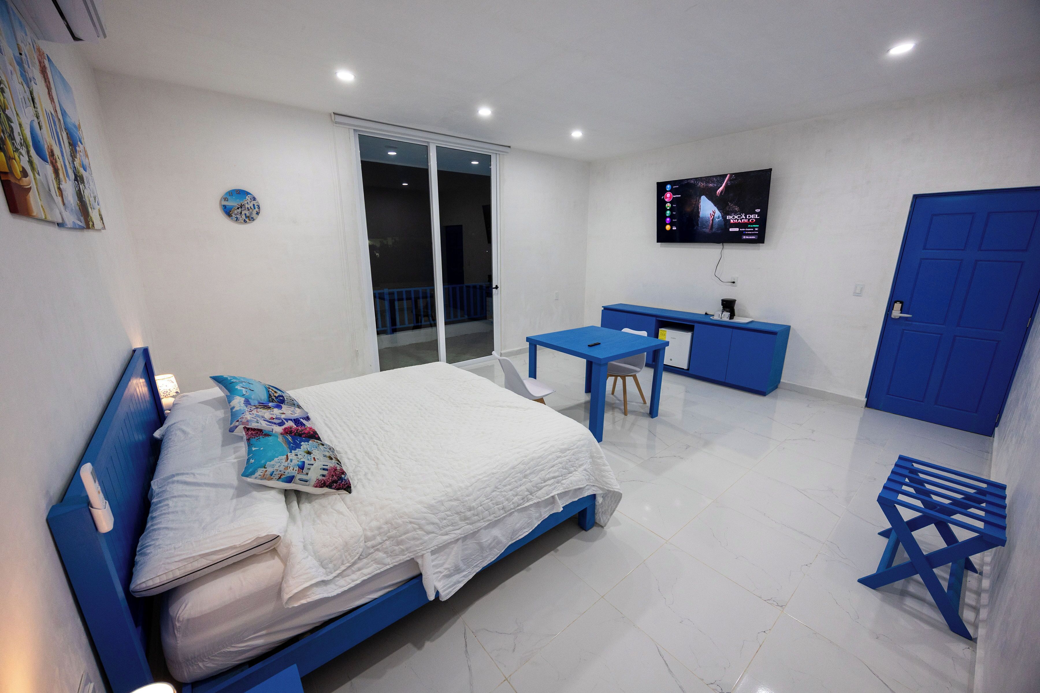 A room with a bed, a desk, a chair, a TV, and a door.