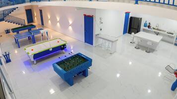 A modern indoor space with a pool table, foosball table, and a kitchen area.