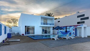 A modern two-story building with a swimming pool, outdoor seating, and a mural. - Have you heard of Santorini? Come experience Santorini in Greece. Themed Hotel (Mérida)