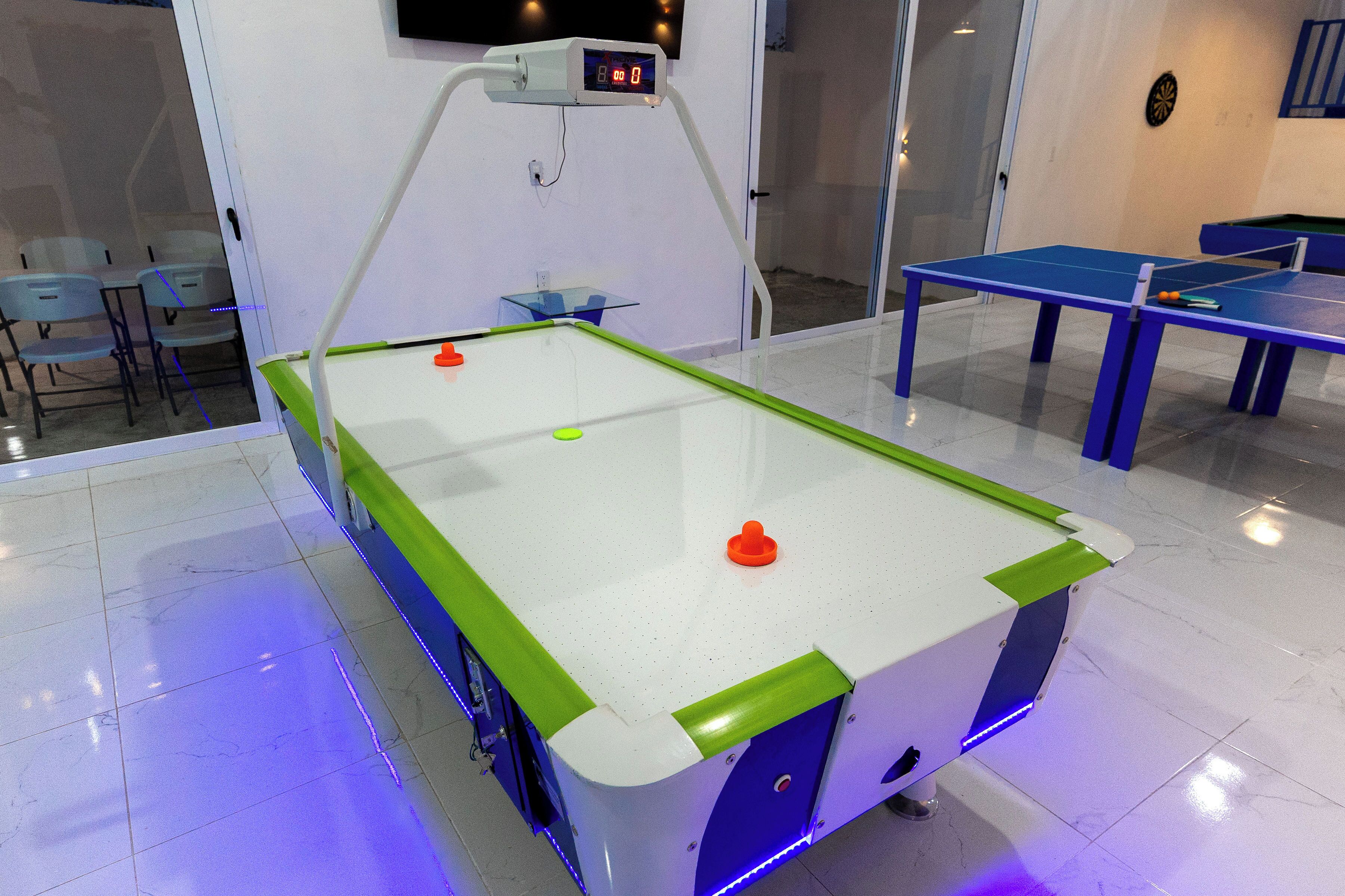 Une table de ping-pong dotée d’un tableau de score numérique, entourée de chaises et d’une autre table de ping-pong.