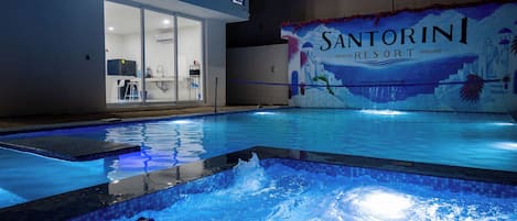 En swimmingpool med utsikt över en byggnad i bakgrunden, där det står ”Santorini Resort”.