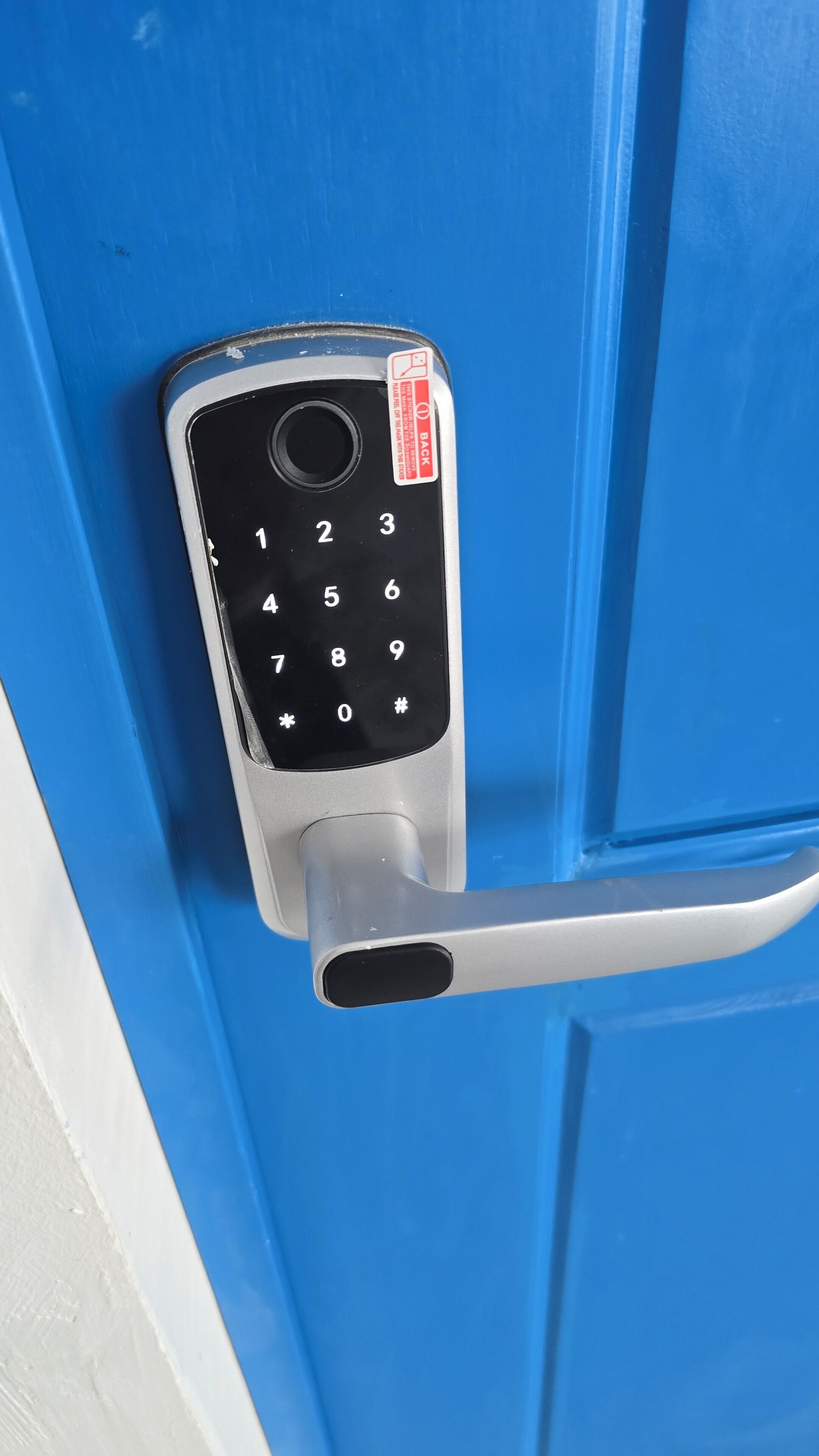 A numeric keypad door lock on a blue door.